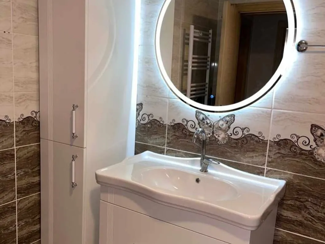 Banyo dolabının üstüne ortalanmış yuvarlak LED ayna